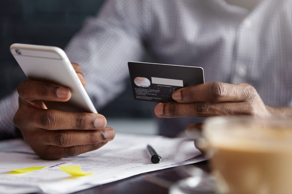 Hands holding a smartphone and a credit card, symbolizing paying with the mobile.