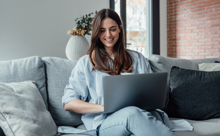 A woman sitting with a laptop and smiling.